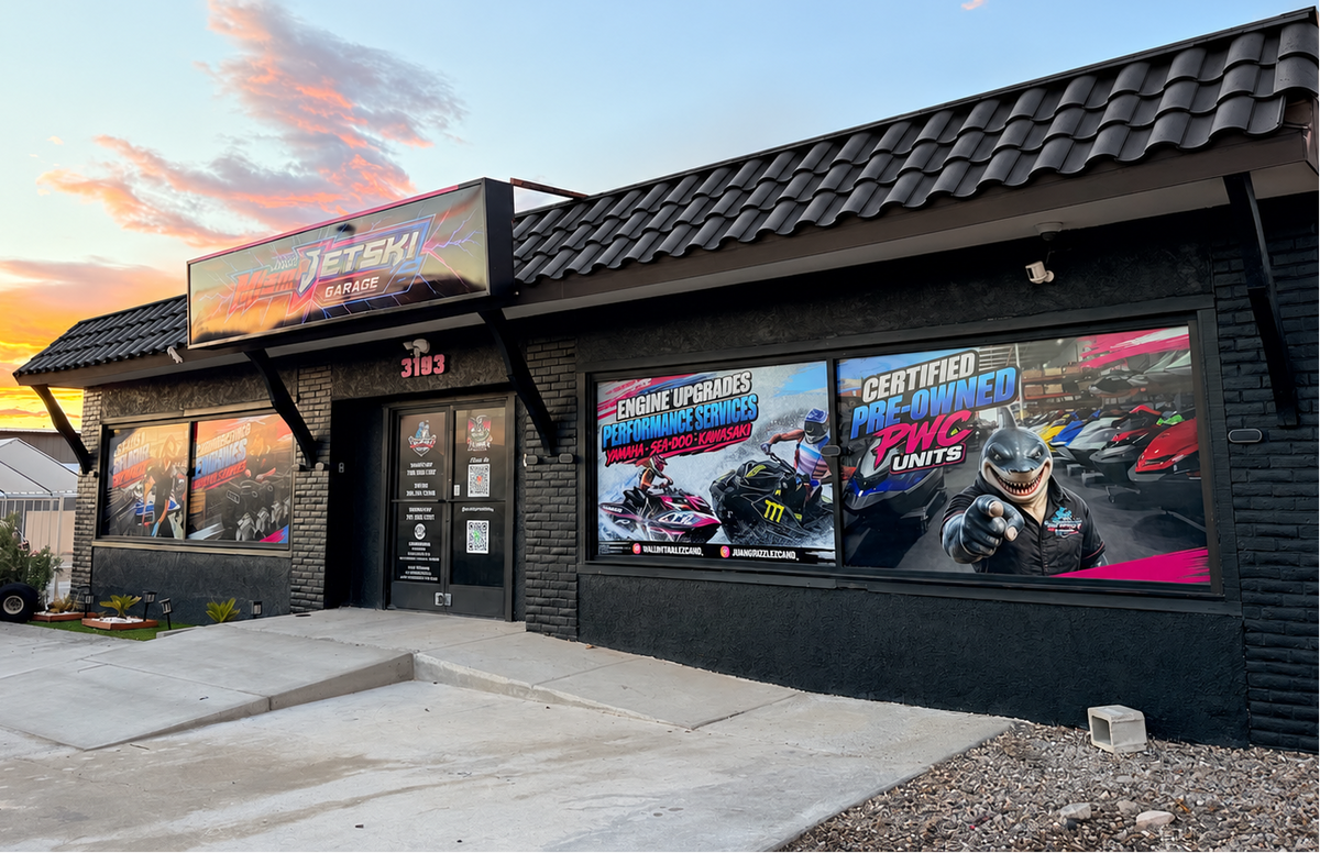 Jet Engine Tuning & Performance LLC storefront at dusk, featuring a black brick exterior, tiled roof, large window decals with racing graphics, and a concrete walkway in front.