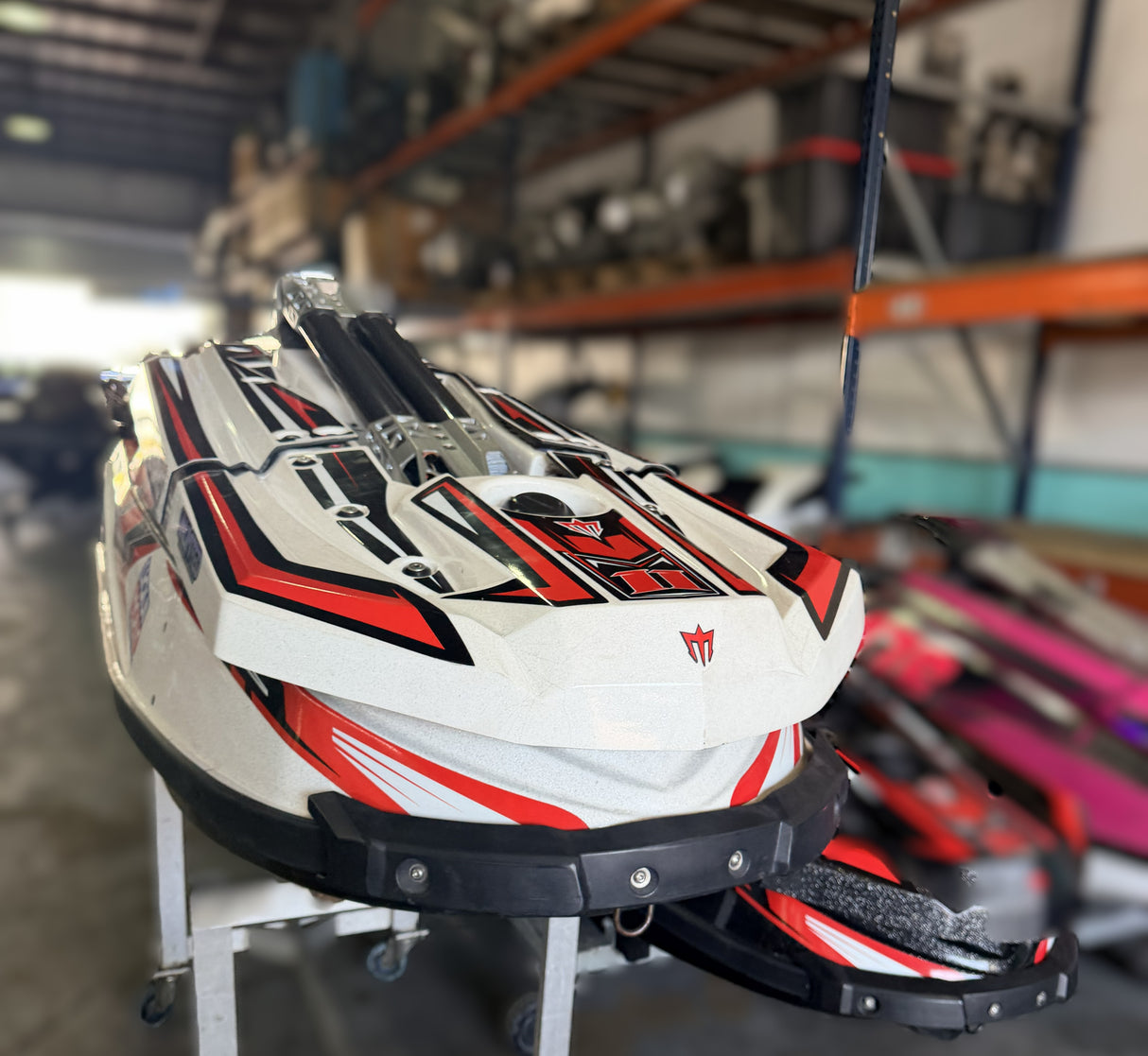White, red, and black watercraft on display in a warehouse setting
