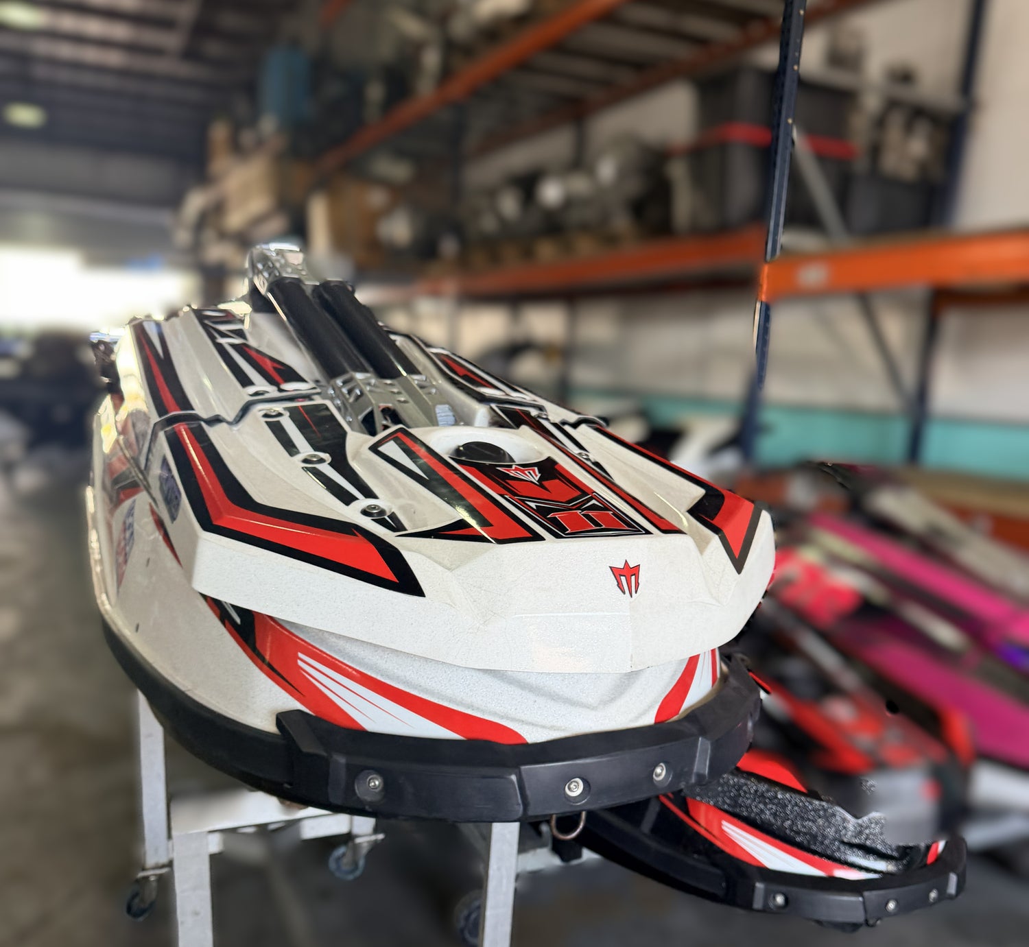 White, red, and black watercraft on display in a warehouse setting
