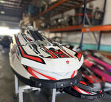 White, red, and black watercraft on display in a warehouse setting