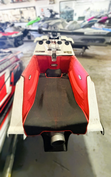 Close-up of a red and black boat seat with visible branding in a showroom setting.