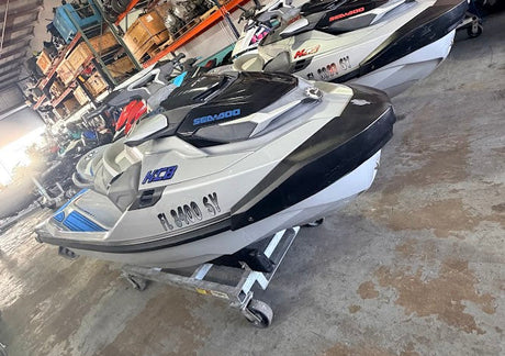 Multiple jet skis in a warehouse setting with shelves and equipment in the background.