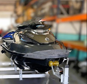 Two jet skis on a trailer in a warehouse setting