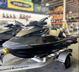 Two jet skis on a trailer in a warehouse setting with various equipment and branding in the background.